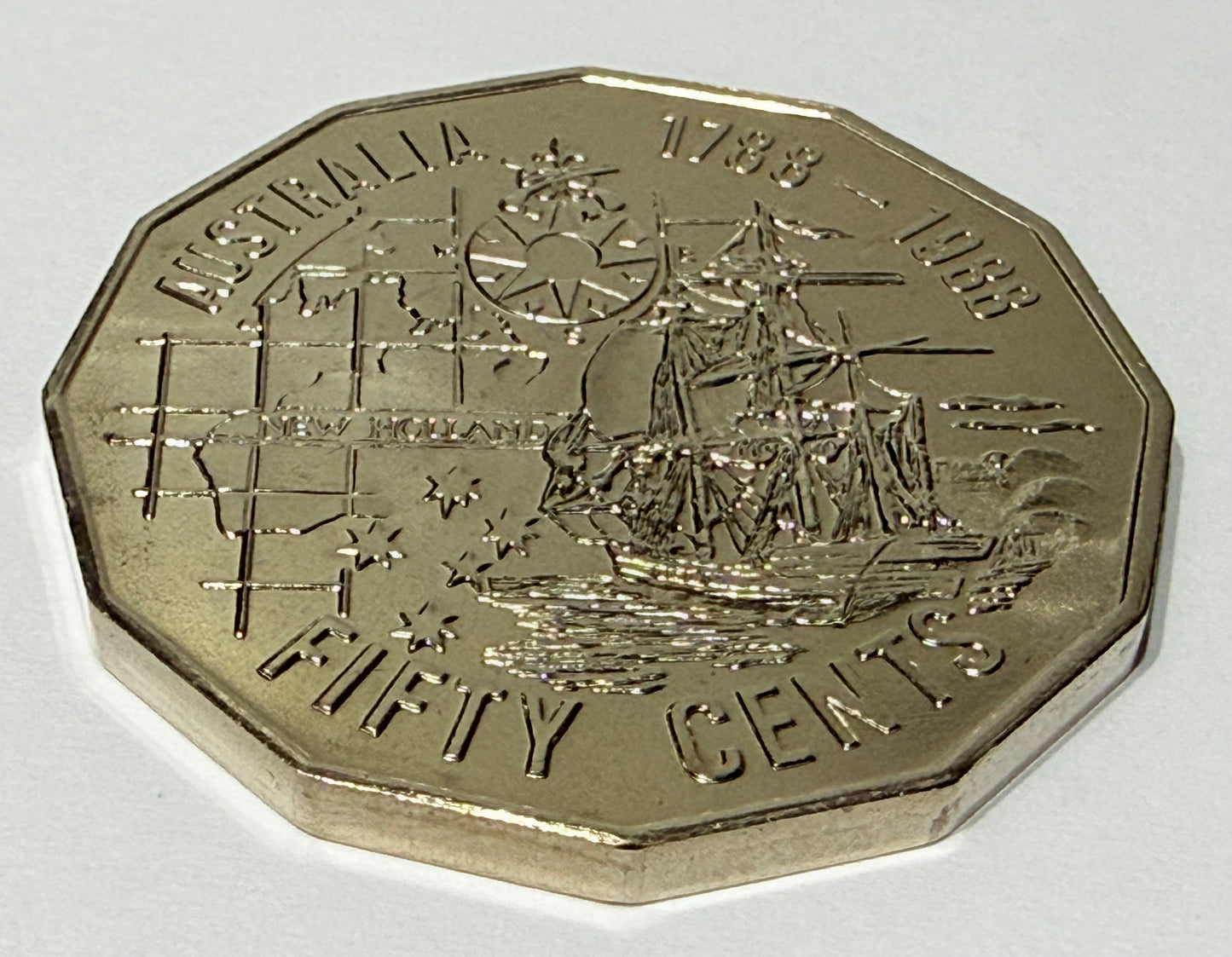 Australian fifty cents coin with ship design on a white background
