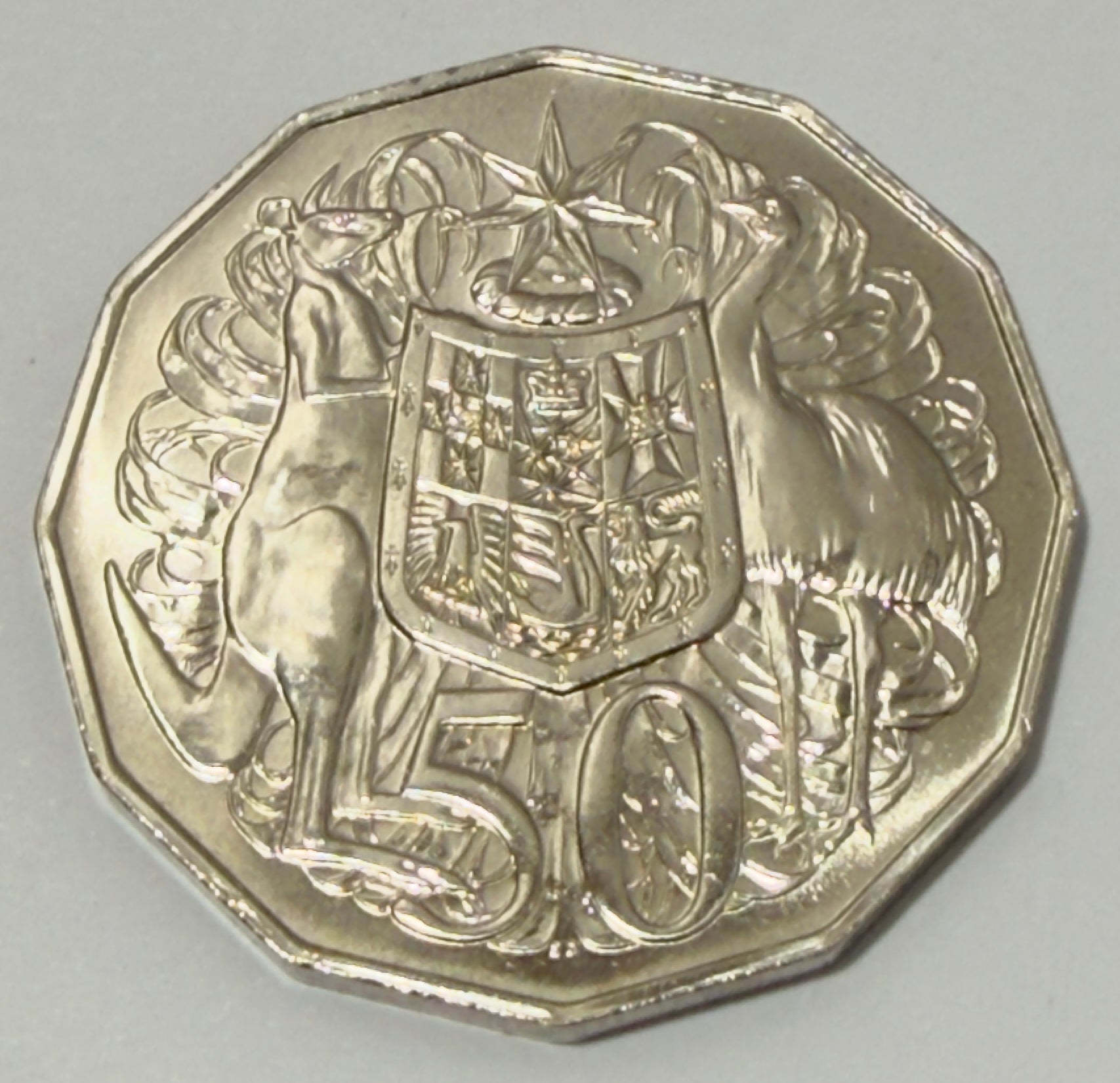 Silver coin with a design of kangaroos and a shield on a gray background